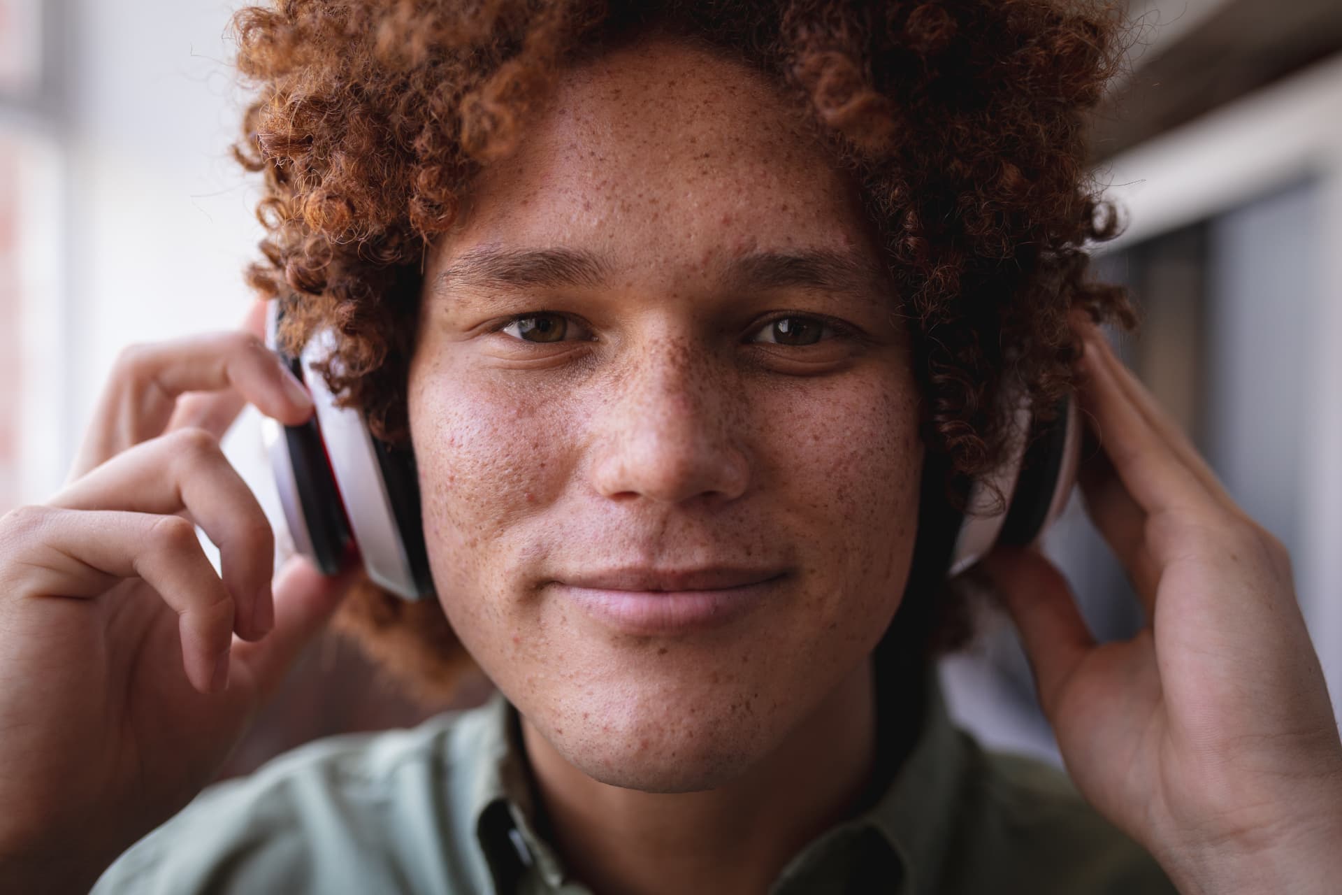Man with curly hair smiling while wearing over-ear headphones