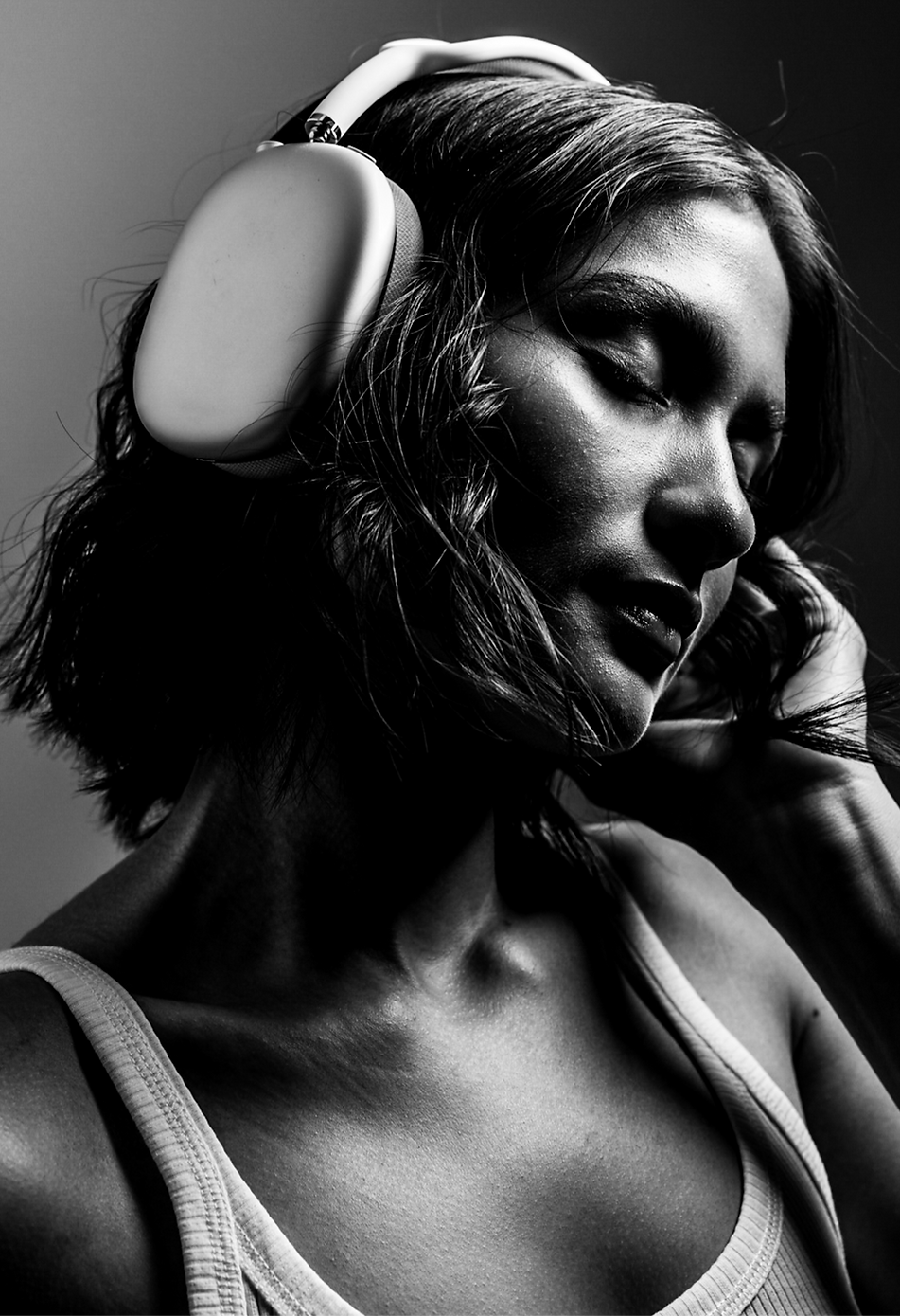 Black and white portrait of a woman wearing large over-ear headphones, eyes closed
